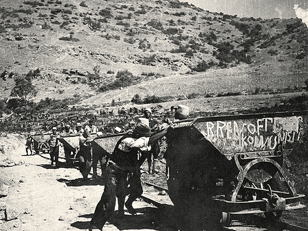 A black-and-white photo of workers moving railway carts.