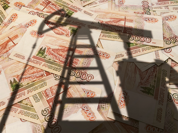 A photo of a pile of Russian currency with a shadow of an oil rig over it.