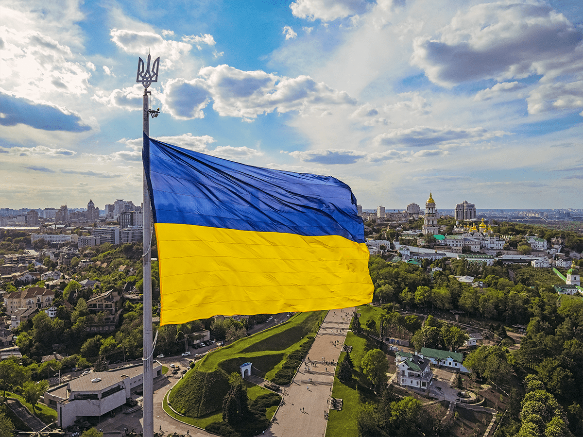 Ukrainian flag with city landscape behind it